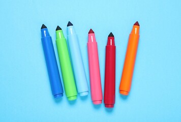 Many colorful markers on light blue background, flat lay