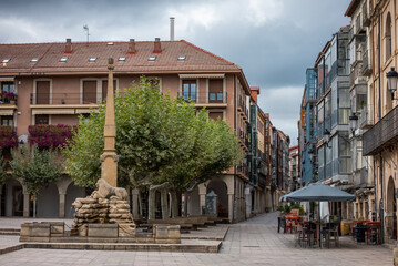 Fototapeta premium Historic square with stone monument and colorful buildings on cloudy day in small Spanish town Soria, local architecture and calm ambiance