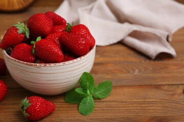 Bowl with sweet fresh strawberries and mint on wooden background