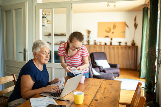 Young granddaughter helping grandmother with online bill payments at home