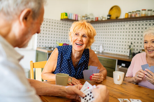 Senior friends playing cards together at kitchen table