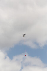Fire fighting helicopter with trailing a water bucket on the way back to a bushfire