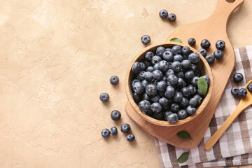 Napkin and wooden bowl of fresh ripe blueberry on pink grunge background