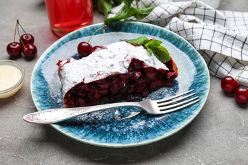 Plate with piece of tasty cherry strudel and napkin on grunge background, closeup