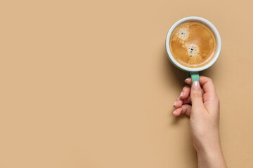 Female hand with cup of coffee on beige background