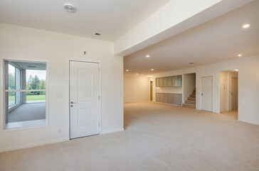 The image shows an empty living room with light-colored walls and carpet.