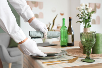 Male waiter setting table in restaurant, closeup