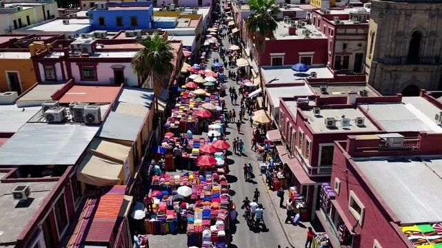 Aerial video view of a vibrant cityscape with colorful buildings and a bustling street market, showcasing a lively urban atmosphere from above.