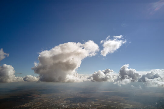 Aerial view from airplane window at high altitude of earth covered with white puffy cumulus clouds