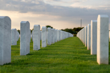 Obraz premium American national military cemetery with rows of white tomb stones on green grass lawn. Memorial Day concept