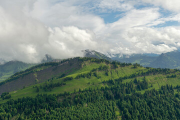 Scenic view of lush green hills and majestic mountains under a cloudy sky during daytime