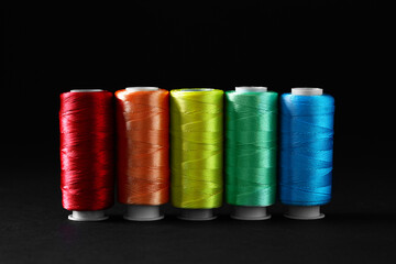 Spools of colorful sewing threads on black background