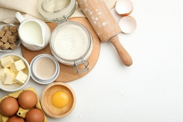 Rolling pin and different ingredients on white table, flat lay. Space for text