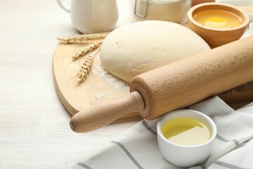 Rolling pin and different ingredients on light wooden table, closeup
