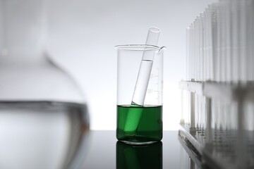 Laboratory glassware with liquid on mirror surface against light background