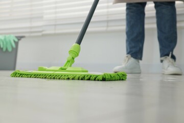 Woman cleaning floor with microfiber mop indoors, closeup