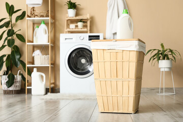 Laundry basket with detergent and  washing machine in room