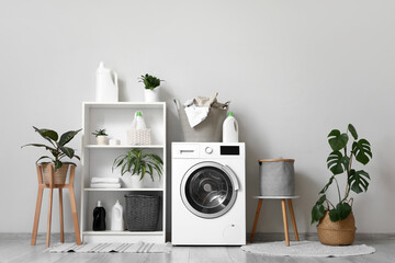 Washing machine, laundry basket and houseplants in interior of bathroom
