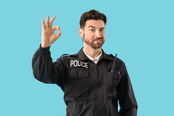 Happy male police officer with radio transmitter showing OK gesture on blue background