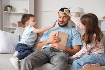 Fototapeta premium Little children painting their father's face while he sleeping at home. April fool's day prank