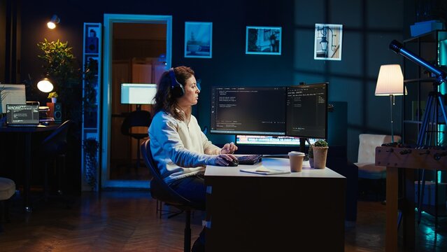 IT programmer listening music while fixing vulnerabilities in software compromising operating system. Cybersecurity expert wearing headphones and using PC to patch security exposures, camera B