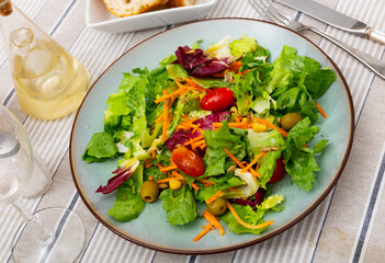 Summer mixed salad of carrot, lettuce, tomatoes and olives closeup