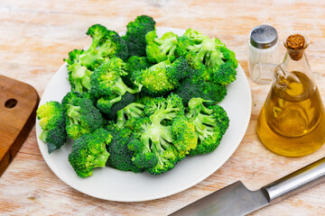 Cutting and cooking broccoli on wooden textured backdrop