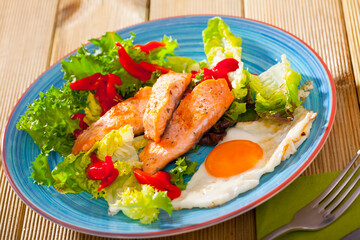 Picture of tasty breakfast with trout, egg, pepper and lettuce at plate on table