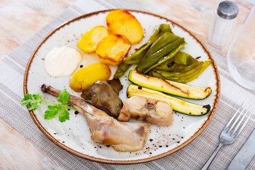 Delicious braised rabbit served with garnish of potato and grilled vegetables and parsley sprig