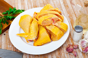 Fresh raw chooped chicken pieces on a plate while cooking in a home kitchen. Decorated with a sprig of fresh greenery, ..vegetable oil, garlic and peppercorns