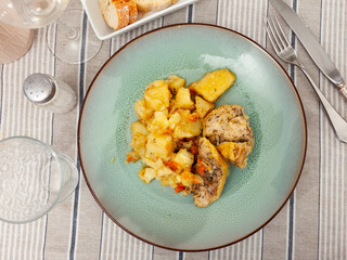 Tasty baked chicken drumsticks and potatoes at plate closeup