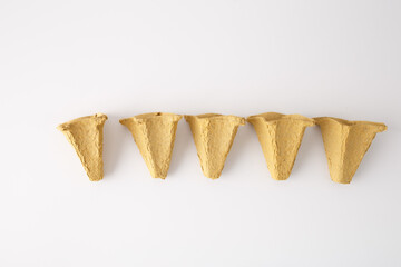 brown paper egg cones are arranged on a white background rough texture, repurpose materials. Step...