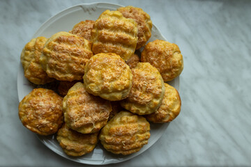 Homemade golden brown cheese scones on a plate on a marble background.







