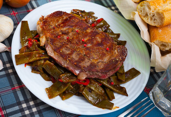Delicious fried beef loin served with vegetable garnish of stewed green beans and red bell pepper