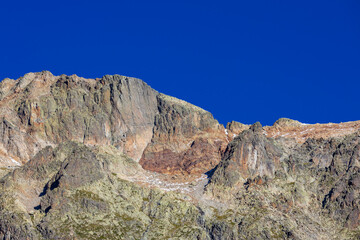 Tour du Mont Blanc beautiful alpine scenic view. Landscape of the summer Alps mountains with pocky peaks, blue ice glacier, green grass and blooming flowers. Alps in Italy and France hiking and trek