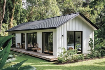 Modern house nestled in lush greenery offering a serene escape surrounded by nature and tranquility, featuring large windows and a wooden deck for relaxation