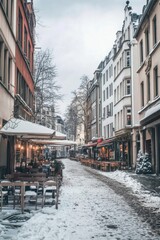 Obraz premium Quiet winter afternoon in a charming cobblestone street lined with cozy cafes and restaurants in a historic European town under a serene blanket of snow