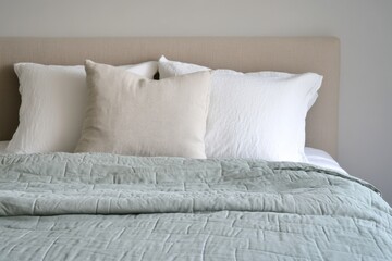 Soft bedding arrangement in a minimalist bedroom featuring a light-colored quilt and fluffy pillows, designed for relaxation and comfort without distractions