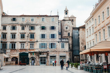 Obraz premium Historic stone building with a clock tower in a European city square, old architecture. Peoples Square Narodni trg in Split, Croatia