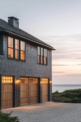 Obraz premium A contemporary coastal home features elegant wooden garage doors, set against a stunning sunset backdrop that overlooks the ocean and is beautifully framed by lush greenery