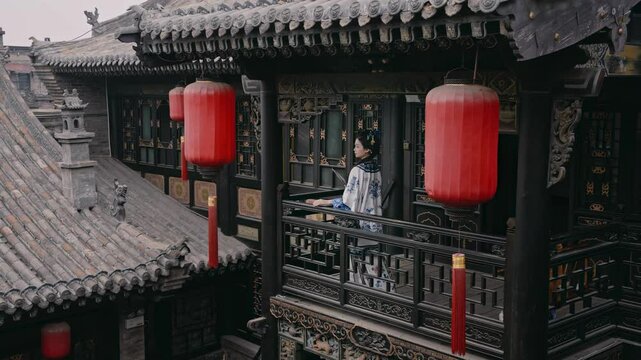 Girl dressed in Jin Merchant costume strolls through Pingyao Ancient City during vibrant lantern lighting