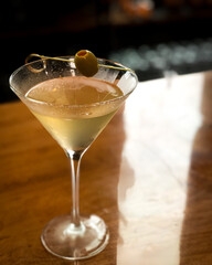 Martini with olive on top set on a wooden surface
