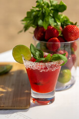 Bright red tropical cocktail with strawberries, lime and basil