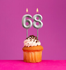 Birthday candle number 68 with cupcake on violet background.