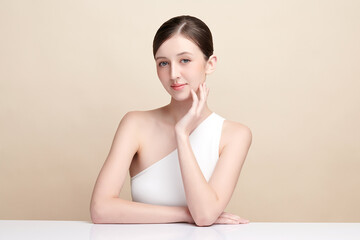 Naklejka premium Beautiful young woman with clean fresh skin on beige background, Face care, Facial treatment, Cosmetology, beauty and spa, women portrait.