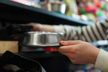 Woman choosing feeding bowl in pet shop, closeup