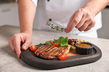 Professional chef serving dish at table indoors, closeup