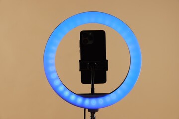 Ring lamp with smartphone on beige background
