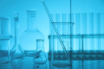 Laboratory glassware on mirror surface against light blue background