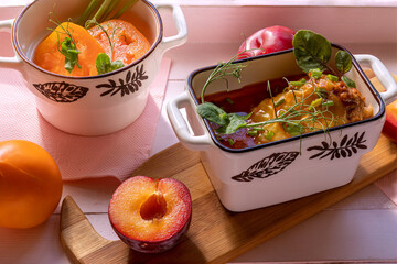 Stuffed pepper and yellow tomato salad in portioned dishes. On wooden tray of pale pink color....